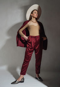 Portrait of young woman standing against wall