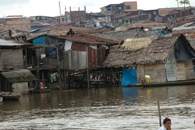 Houses by river against buildings