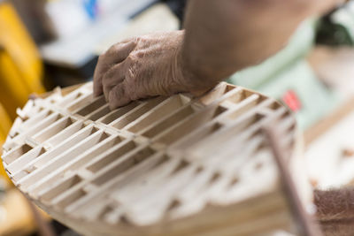 Close-up of man working on wooden boat model