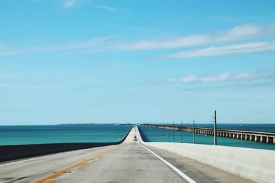 Empty road by sea against sky