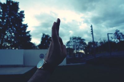Close-up of hand against sky