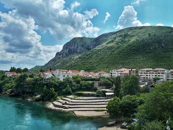 Scenic view of river by buildings against sky