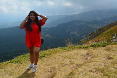 Full length of woman standing on mountain against sky