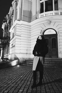 Full length of woman standing on footpath against building