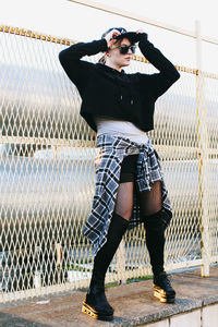 Portrait of young woman standing against chainlink fence.construction net. korean fashion. european.