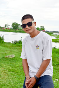 Portrait of young man wearing sunglasses standing on field