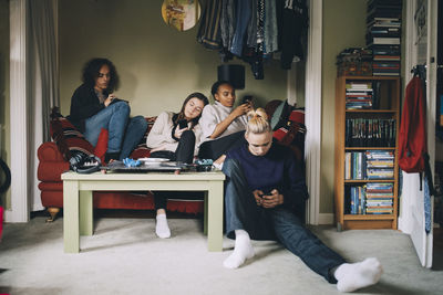 Distracted friends using smart phones while sitting together at home