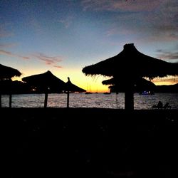 Silhouette built structure on beach against sky during sunset