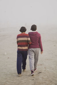 Rear view of couple walking on beach