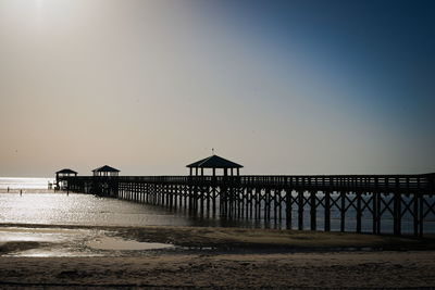 Pier over sea against sky during sunrise