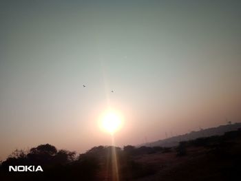 Low angle view of sun shining in sky during sunset