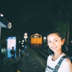 Portrait of smiling woman standing on illuminated bus