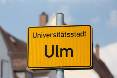 Close-up of yellow sign against sky