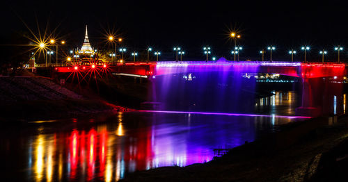 Illuminated bridge over river in city at night