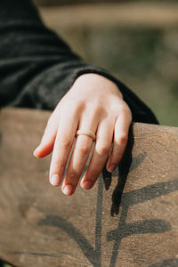 Cropped image of woman wearing ring sitting on bench outdoors