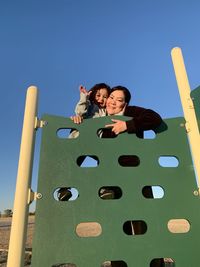 Low angle view of friends on wooden structure against sky