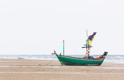 Fishing boat on beach against clear sky