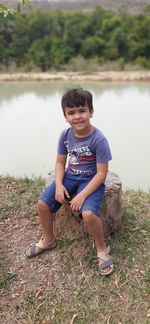 Portrait of smiling boy sitting by lake