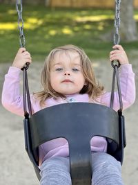 Portrait of cute girl sitting on swing at playground