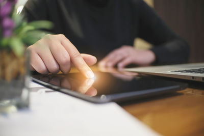 Midsection of man using mobile phone on table