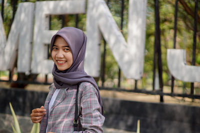 Muslim female student wearing hijabs smile in front of the park
