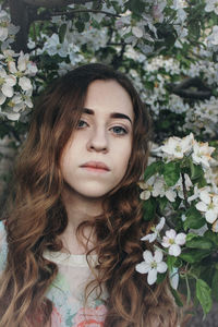 Portrait of woman standing against flowering plant