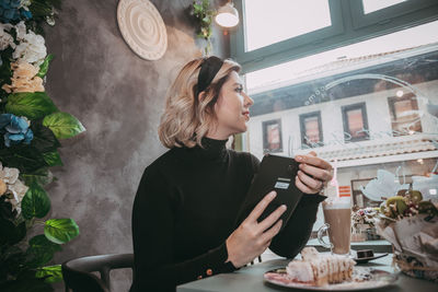 Young woman looking away while sitting on table