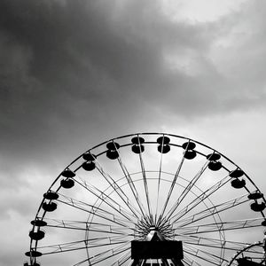 Low angle view of ferris wheel against cloudy sky