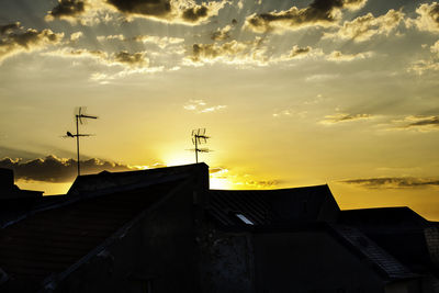 Low angle view of silhouette house against sky during sunset