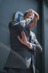 Portrait of handsome young businessman in grey classic suit. standing near dark green building