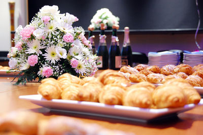 Close-up of croissants in plate with bouquet on table