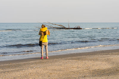 Rear view of man standing on beach against sky