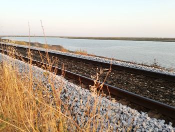 Railroad tracks by sea against clear sky