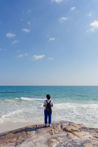 Rear view of men standing at beach against sky