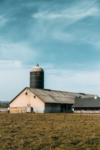 Barn on field by building against sky