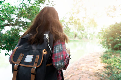 Rear view of woman standing against trees