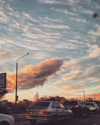 Cars on street against dramatic sky