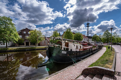 Boats moored on river by buildings against sky