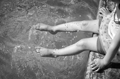 Low section of playful girl sitting on jetty by river