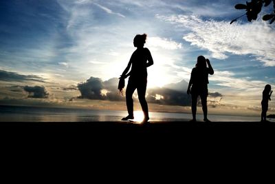 Silhouette of people on beach at sunset