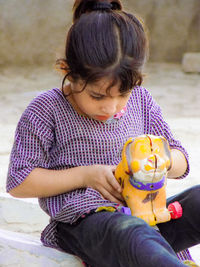 Close-up of girl with toy sitting outdoors