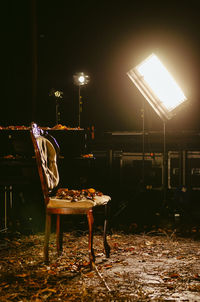 Empty chairs and table against illuminated street at night