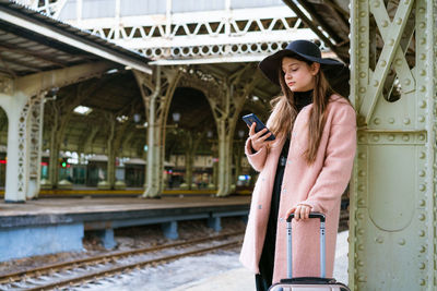 Beautiful young woman waiting for train at train station for travel in autumn. person