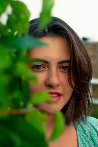 Close-up portrait of beautiful young woman by plants