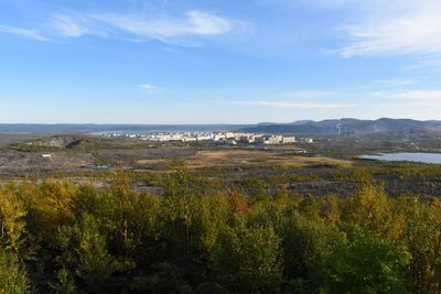 Scenic view of green landscape and sea against sky