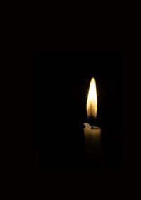 Close-up of lit candle in darkroom