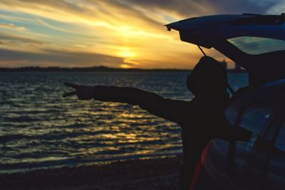 Silhouette person on beach against sky during sunset