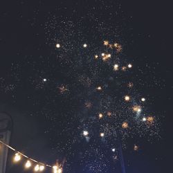 Low angle view of fireworks against sky at night