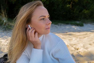 Happy young woman on the beach sea ocean. wearing wireless headphones doing audio healing sound