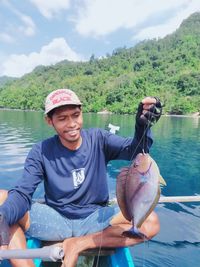 Portrait of smiling man holding boat in lake